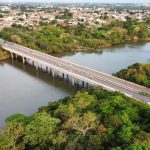 Vista aérea de uma ponte sobre um rio, cercada por vegetação, em Mato Grosso.