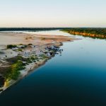 Vista aérea do rio Araguaia, com um acampamento às margens e vegetação ao redor.